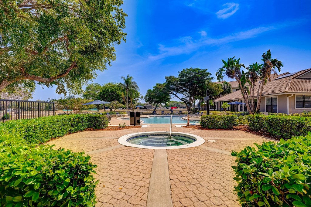 a fountain in the center of a garden with a pool